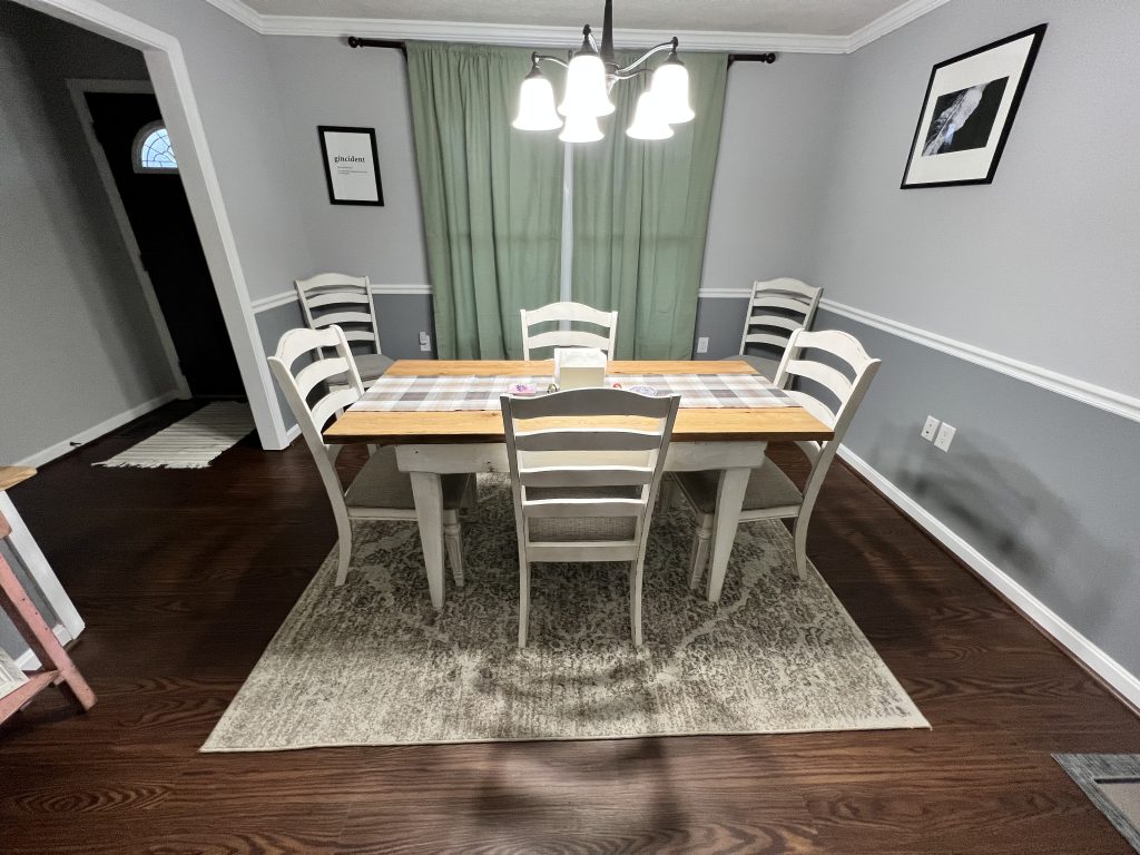 Dining room table made by Shenandoah Primitives with four white chairs, a table runner and sage green curtains in the background